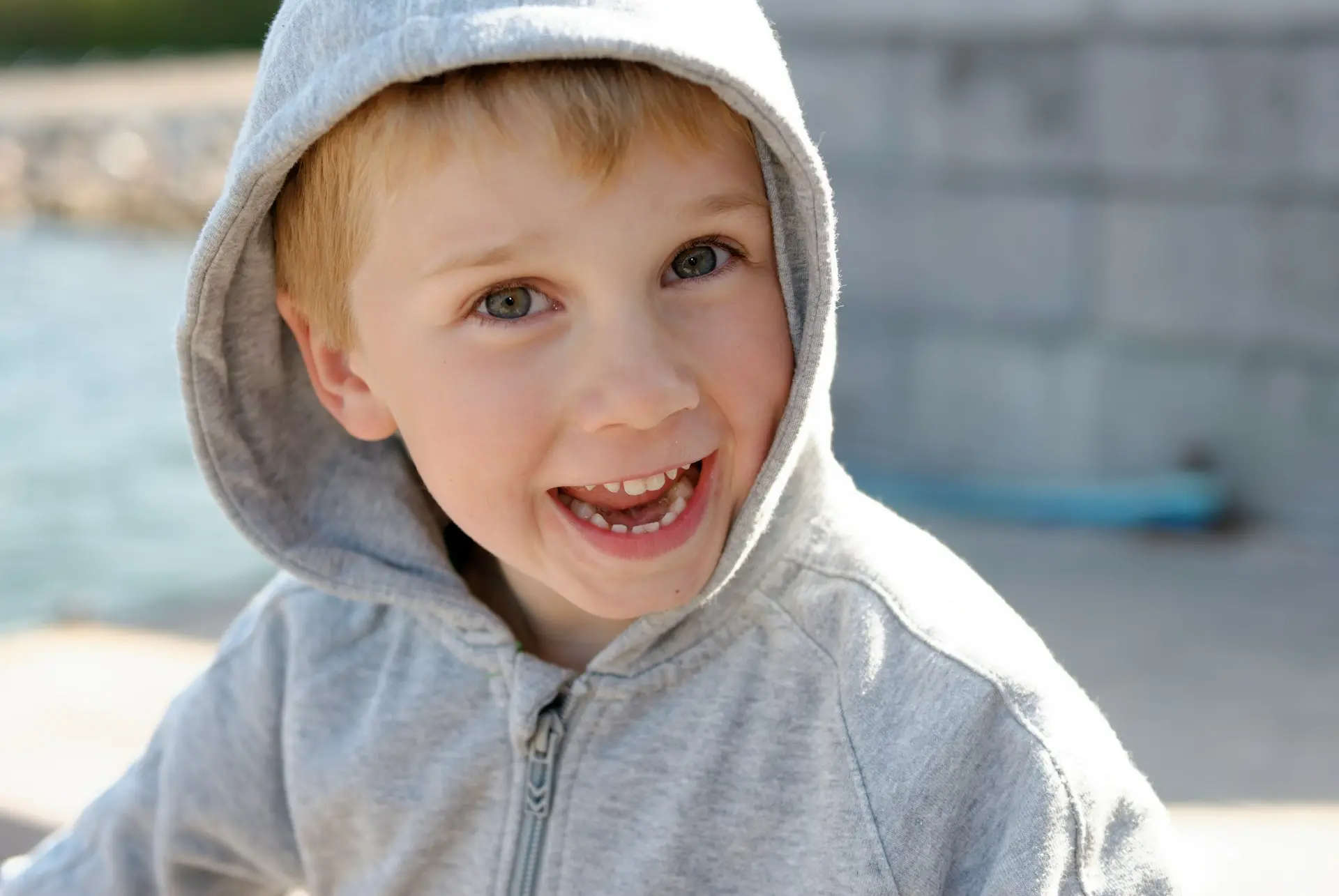 a young boy wearing a gray hoodie and smiling